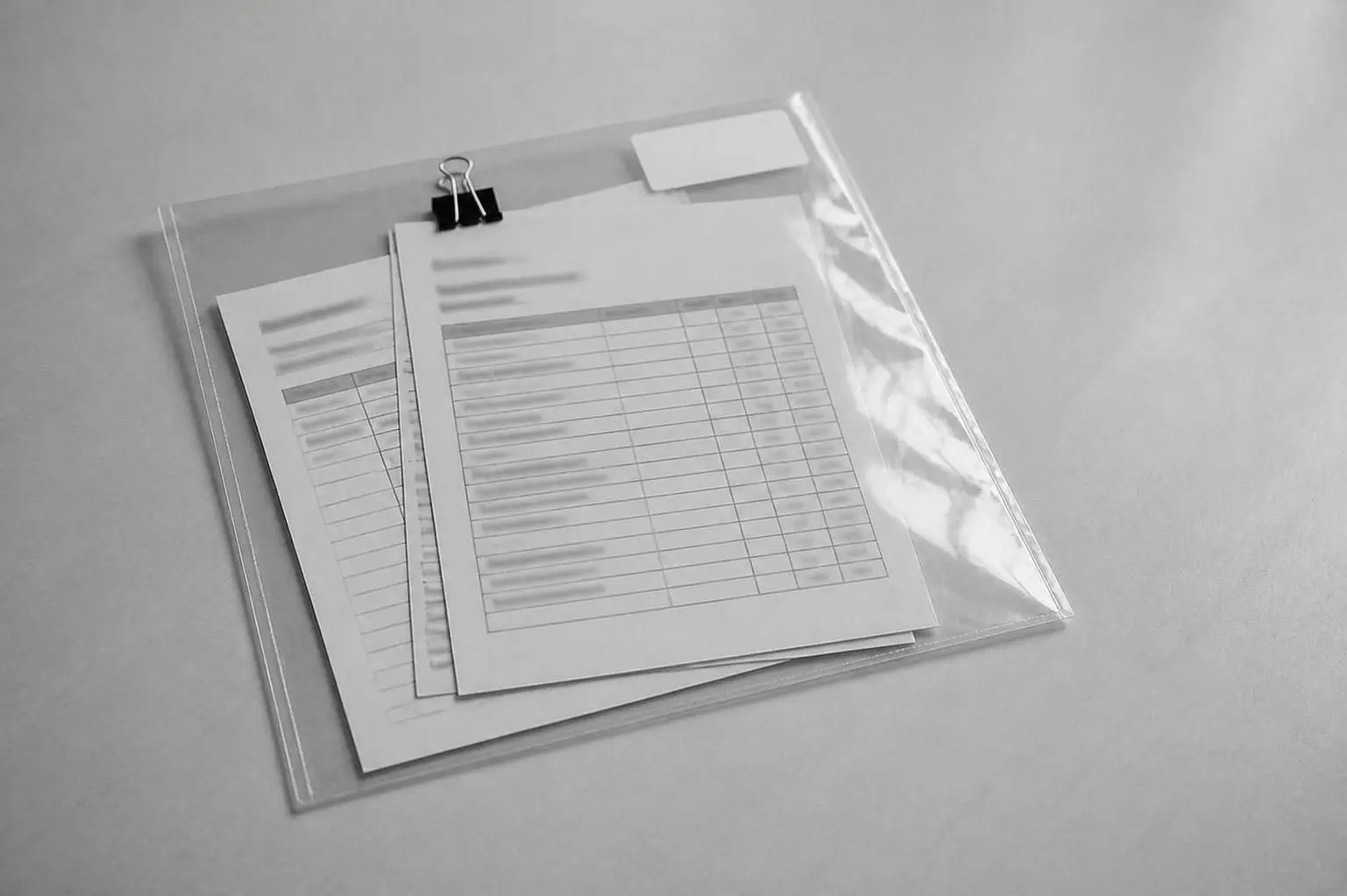 A clear plastic sleeve with three clipped sheets of paper and a blank name label